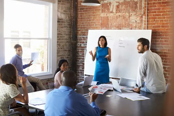 A team meeting around a table in a brick-walled loft office